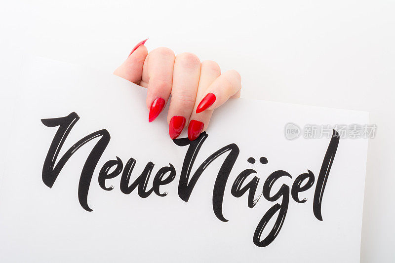 修了新指甲的女人在纸上举着“neue nägel”这个词